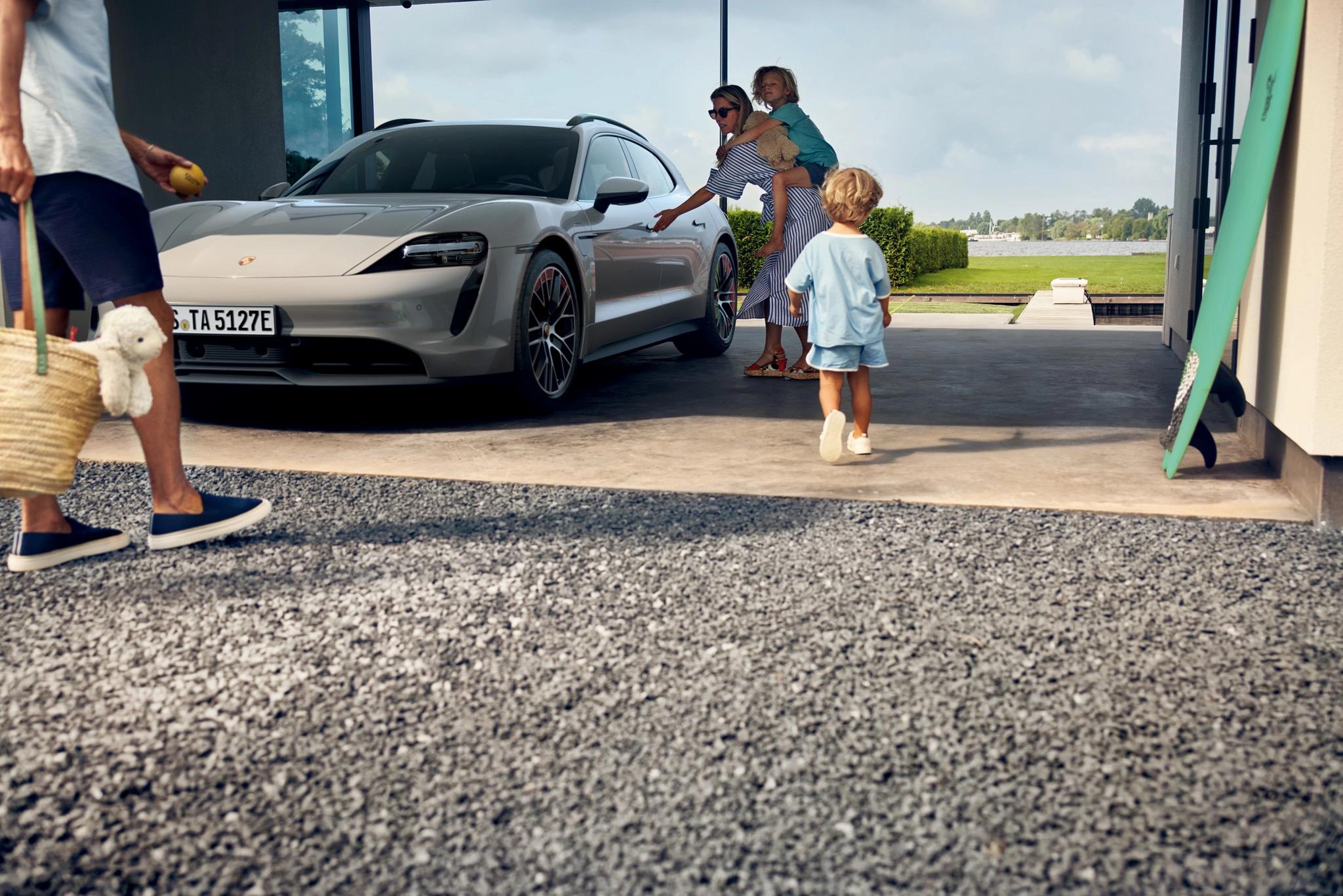 Porsche Taycan in einer offenen Garage. Eine Familie bereitet sich auf einen Strandurlaub vor.